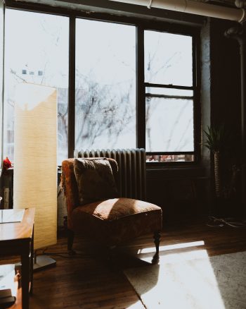 A chair in front of a window with sunlight coming through the windows.